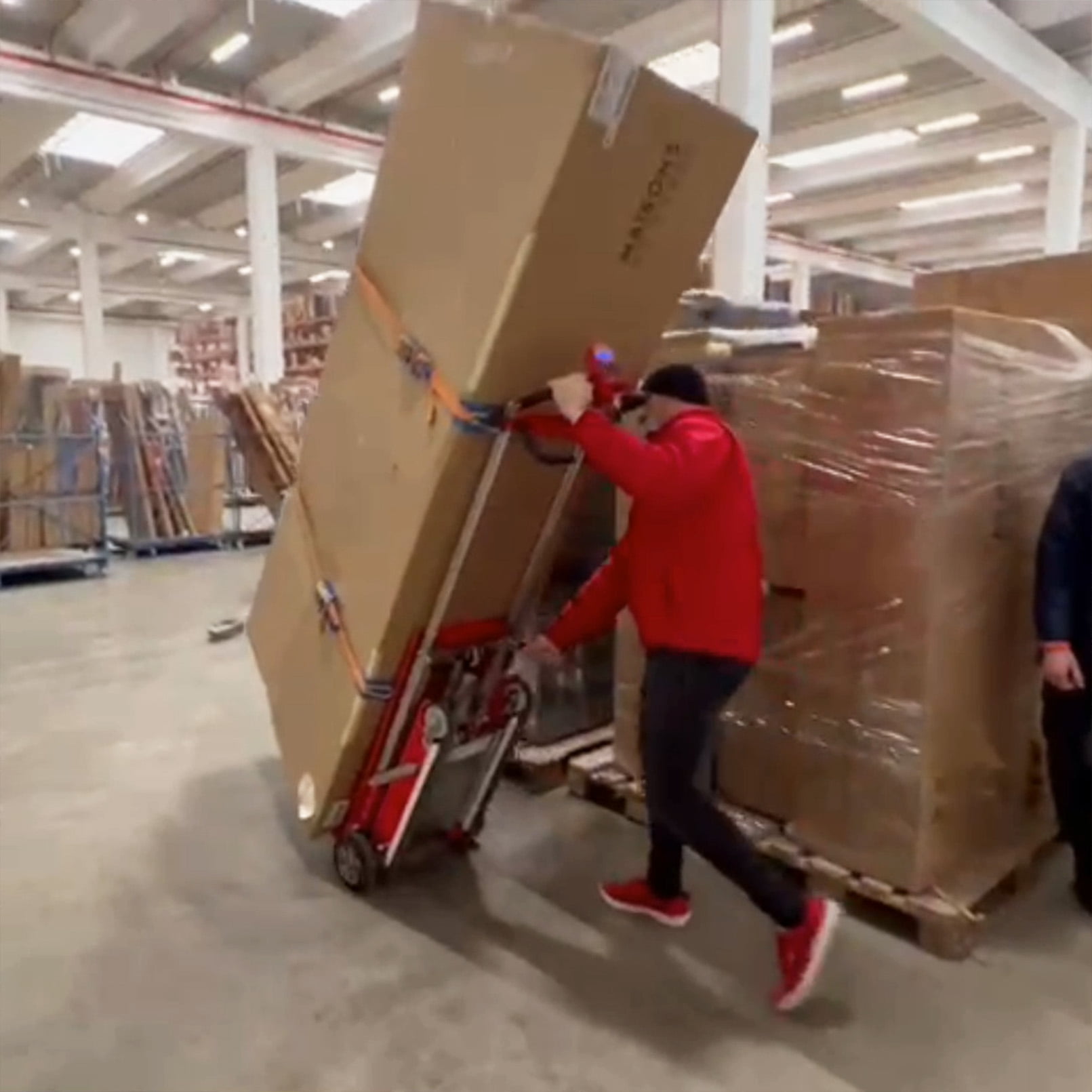 Transport d'un meuble dans un entrepôt de marchandises avec le diable électrique d'escalier Buddy Lift