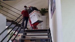 Un homme transporte la photocopieuse dans les escaliers avec le chariot d'escalier Domino